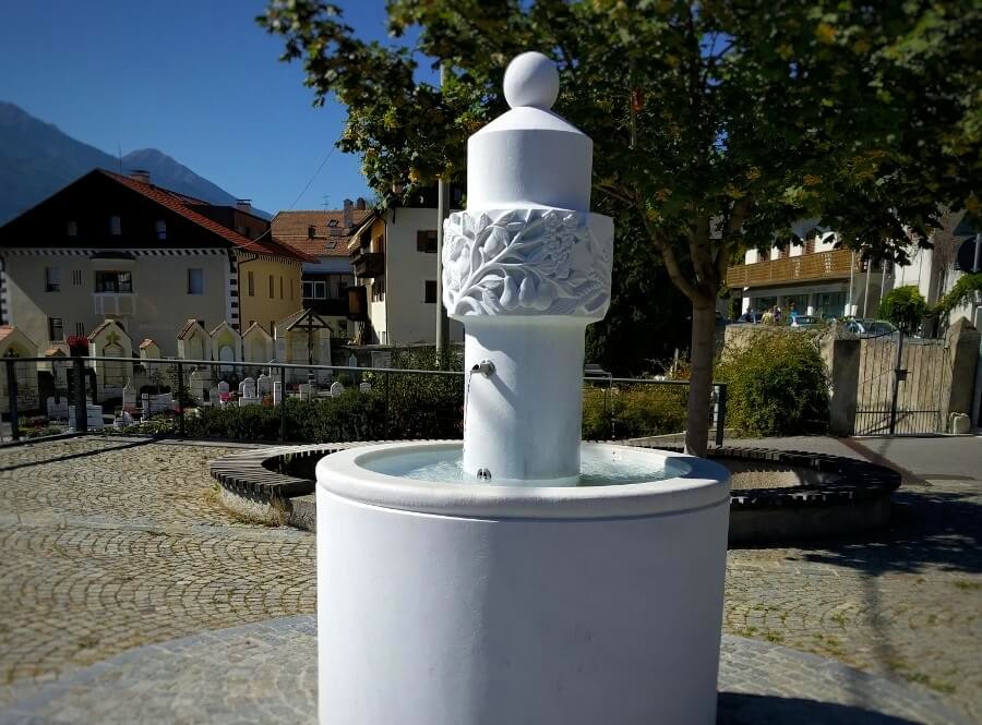 Unser Startpunkt: Der Brunnen aus Göflaner Marmor an der Kirche von Kortsch